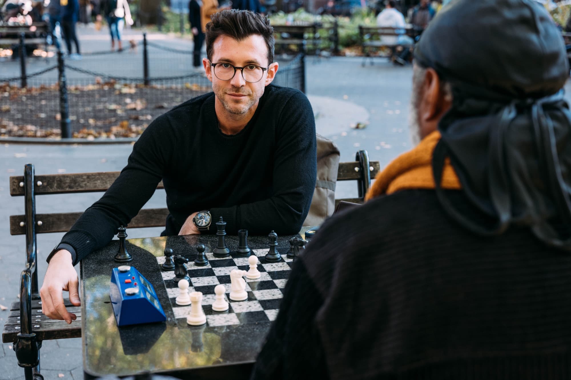 Nick Sonnenberg playing speed chess against an opponent at a stone table in a New York park.